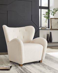 a white chair sitting on top of a rug next to a black and white wall