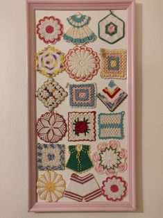 a pink frame with some crocheted items hanging on it's side and a white wall in the background