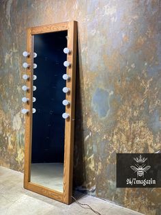 a mirror sitting on top of a floor next to a wall covered in stones and lights