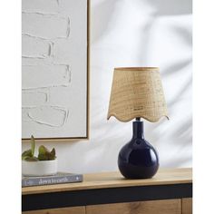 a blue vase sitting on top of a wooden table next to a book and lamp