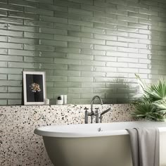 a bath tub sitting next to a green brick wall