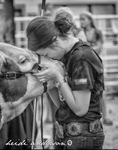 a woman is kissing a cow with her hand