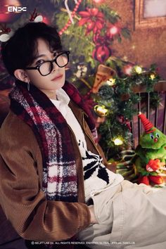 a boy wearing glasses sitting on a chair in front of christmas decorations