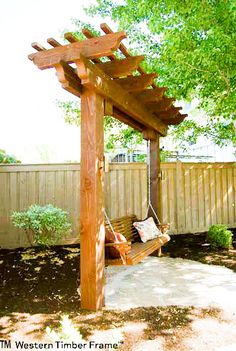 a wooden bench sitting under a tree next to a covered area with a hammock