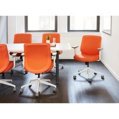 an orange office chair sits in front of a white table with four chairs around it