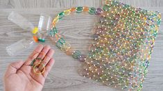 someone is holding their hand out to make a string art project with beads and plastic bottles