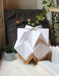 an origami sculpture sitting on top of a table next to a book and potted plant