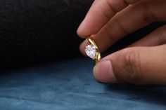 a person holding a ring with a diamond in it's middle and the other hand