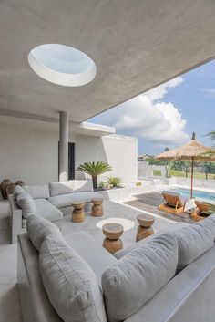 an outdoor living area with couches and tables next to a swimming pool in the background