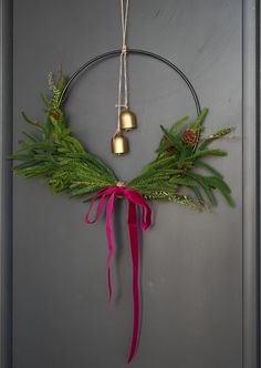 a circular wreath with bells hanging from it's sides and tied to the wall