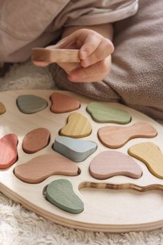 a child is playing with wooden shapes on the floor in front of a pillow and blanket