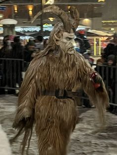 a man dressed as a horned animal walking in the snow