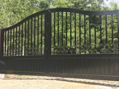 an iron gate is shown in front of some trees and bushes on the other side