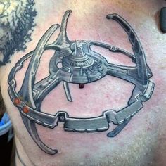 a man with a tattoo on his chest has a sci - fi object in the middle