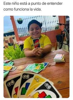 a young boy sitting at a table with playing cards in front of him and the caption reads, mi amix uno yo