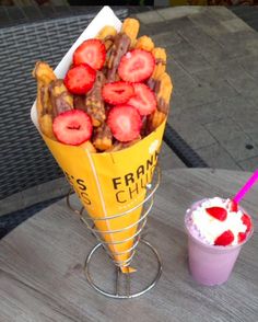 strawberries and other fruit are in a cone on a table next to a drink