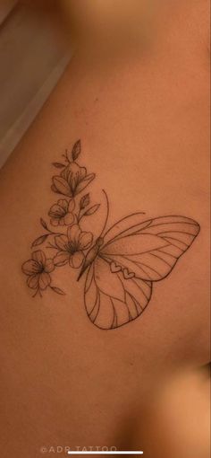 a butterfly tattoo on the back of a woman's stomach, with flowers growing out of it