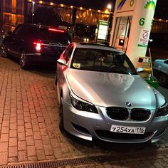 two cars parked next to each other in front of a gas station at night time