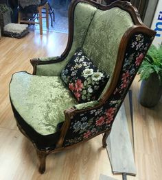 an old chair is sitting on the floor in front of a plant and other furniture