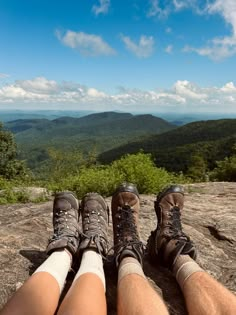 two people sitting on top of a mountain with their legs crossed