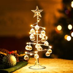 a lighted christmas tree on a table with lights in the shape of stars and baubies