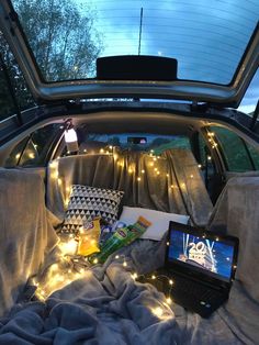 a laptop computer sitting on top of a bed in the back of a car with lights