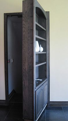 a tall wooden cabinet sitting inside of a room next to a wall with white vases on it