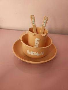 three cups and saucers with spoons in them on a pink tableclothed surface