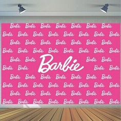 a pink backdrop with the word barbie on it and white letters in front of wooden flooring