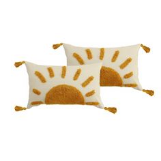 two yellow and white pillows with tassels on the sides, one has an orange sun design