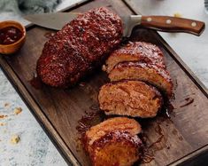 meatloaf with sauce on a cutting board next to a knife