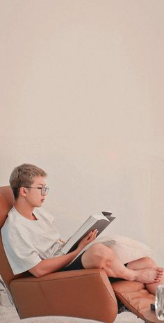 a boy sitting in a chair reading a book