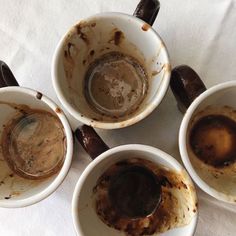 four dirty coffee cups sitting on top of a white table