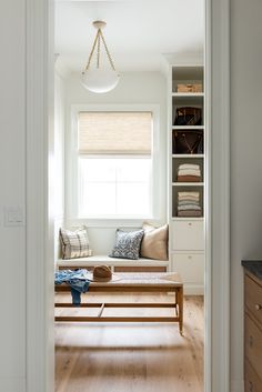 an open door leading to a living room with white walls and wood flooring on the other side