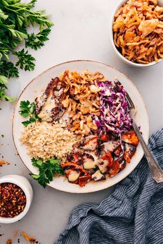 a white plate topped with meat and rice next to bowls of sauces on a table