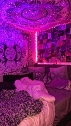 a bed in a room with purple lights on the ceiling and pictures hanging above it