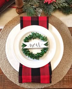 the place setting is decorated with red and black plaid napkins, greenery, and an acorn wreath