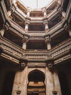 the inside of an old building with stone columns and arches on each side, looking up at the sky