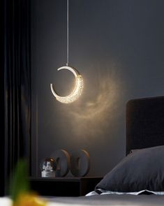 a bedroom with a bed, night stand and hanging light in the middle of it