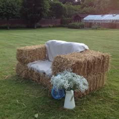 a chair with a blanket on it sitting in the grass next to a vase filled with baby's breath flowers