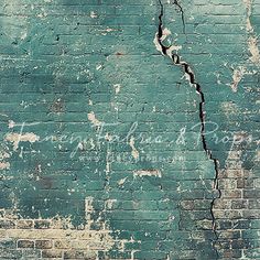 an old brick wall that has been cracked and is green with white writing on it