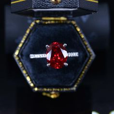 a close up of a ring with a red stone in it on a black surface