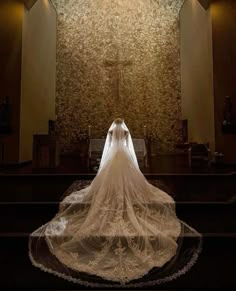 the back of a bride's wedding dress in front of a church alter with lights on