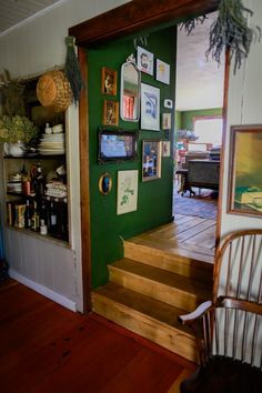 there is a green wall with pictures on it and wooden steps leading up to the door