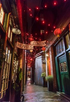 an alleyway with lights strung from the ceiling and signs above it that read heart's content