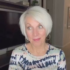 an older woman with white hair and blue eyes is holding a cup in her hands