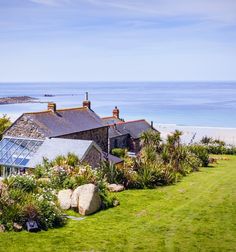 an aerial view of a house on the beach with ocean in the background and grass around it