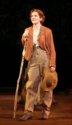 a man with a hat and cane standing in the dirt