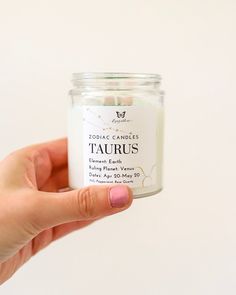 a hand holding a jar of tacurus candles