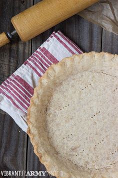 an uncooked pie sitting on top of a table next to a rolling pin